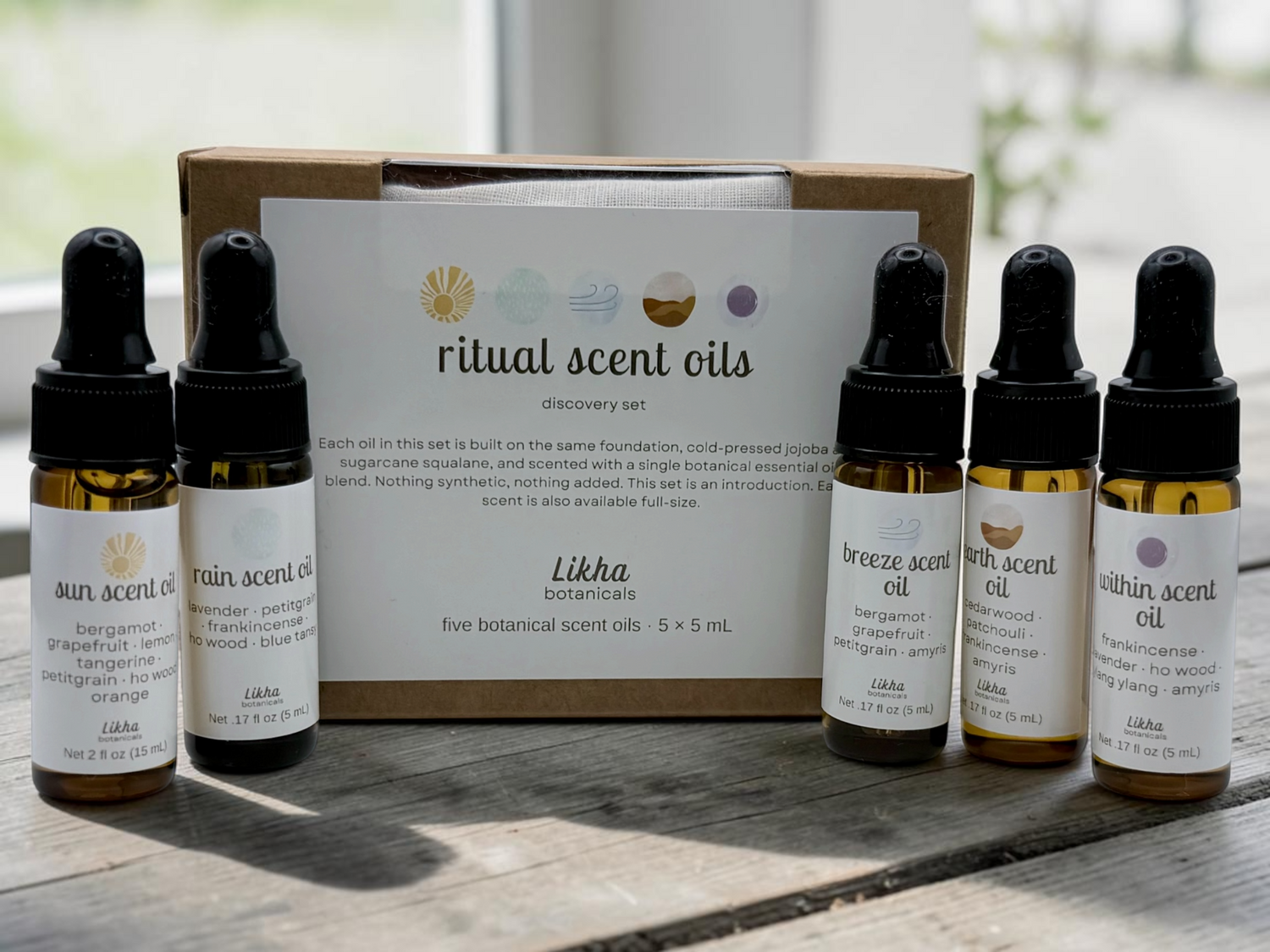 Set of ritual scent oils with a branded box on a wooden surface.
